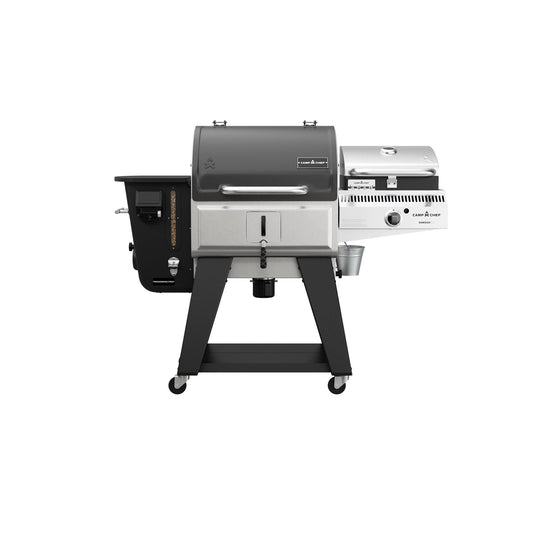 The Camp Chef Woodwind Pro 24 is a black and stainless steel pellet and gas grill with two separate chambers, a Smoke Box for cold smoking or wood pellets, control knobs, thermometer, and four durable wheels for easy mobility.