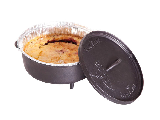A Camp Chef Disposable Dutch Oven Liner with a baked pie inside sits in a three-legged Dutch oven. The lid is partially open, showing the pie and the liner—a classic Dutch oven cooking scene set against a white background.