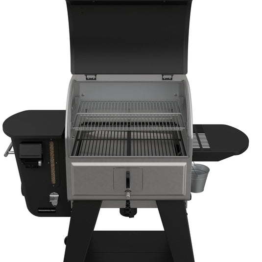The Camp Chef Woodwind Pro 24 pellet grill, shown with the lid open, features two cooking racks, side shelves, a left-side control panel, and a right-side grease collection bucket. It uses wood pellets as fuel.