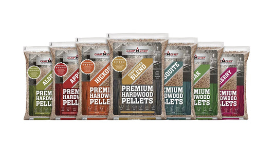 Eight bags of Camp Chef Hardwood Pellets—Alder, Apple, Hickory, Oak, Cherry, Competition Blend, and Mesquite—are lined up side by side for a rich smoke flavor in your grilling.