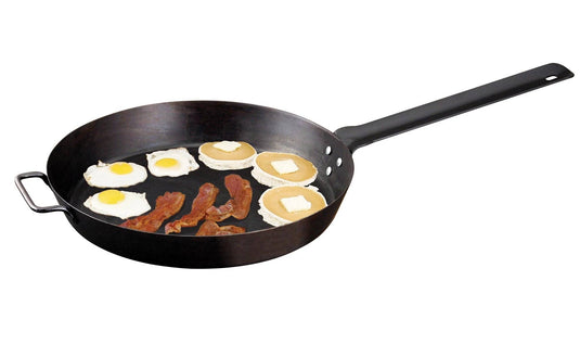 The Camp Chef Lumberjack Skillet - 16” features a long handle and holds three strips of cooked bacon, three sunny-side-up eggs, and three pancakes with butter. Made from seasoned steel, it’s ideal for hearty breakfasts.
