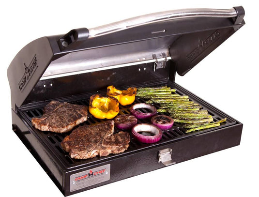 The Camp Chef BBQ Grill Boxes 16 features cast iron grates, shown here with the lid partially open while grilling two steaks, yellow bell pepper halves, sliced red onions, and asparagus spears to perfection.