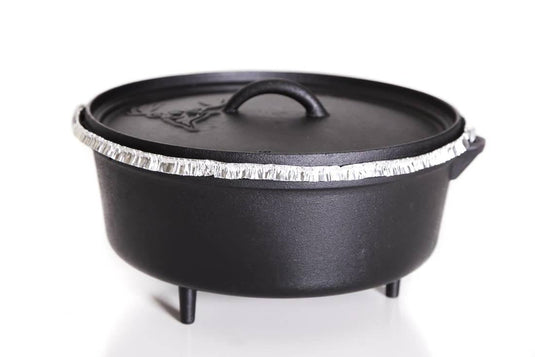 A deep Dutch oven with three short legs and a fitted lid, lined with a Camp Chef Disposable Dutch Oven Liner, sits against a white background—ideal for mess-free Dutch oven cooking.