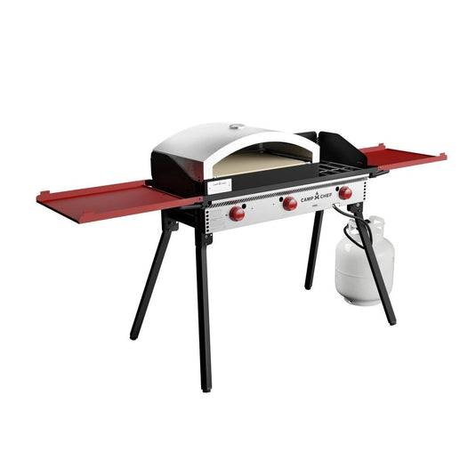 The Camp Chef Pizza Oven 16 - 2 Burner is a portable outdoor gas grill with an artisan pizza oven and ceramic stone, red control knobs, two foldable red side shelves, black legs, and a connected white propane tank.