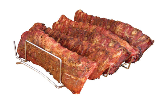 Three racks of seasoned, smoked pork ribs rest on the Camp Chef Rib Rack, isolated on a white background. The ribs look roasted in a smoker, featuring a slightly charred and crispy exterior.