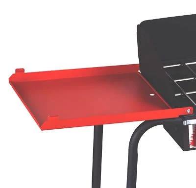 Load image into Gallery viewer, A close-up of the Camp Chef Stove - Side Shelf Set in red, attached to a black grill, with part of the grill grate and frame visible—ideal for adding extra prep space to your outdoor cooking setup.
