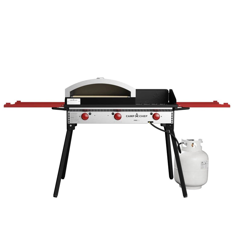 Load image into Gallery viewer, The Camp Chef Pizza Oven 16 - 2 Burner features a ceramic pizza stone, two red control knobs, a propane tank on the right, two red folding side shelves, and four sturdy black legs for outdoor cooking.
