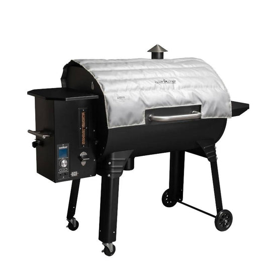 The Camp Chef Pellet Grill Blanket is a fire-resistant cover for the main cooking chamber, compatible with grills featuring a smokestack, side shelf, control panel, and wheels—ideal for cold weather grilling and easy transport.