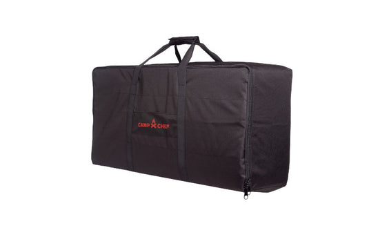 A black, rectangular Camp Chef Compact Stove Carry Bag with zipper and two handles, featuring the red Camp Chef logo on the side, displayed on a white background. Ideal for carrying your portable stove.