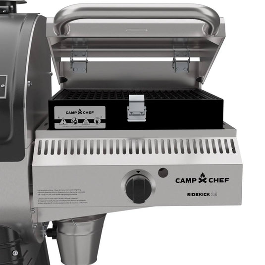 A Camp Chef Sidekick stainless steel gas grill with an open lid, black grill box, and control knob—perfect for pairing with the Camp Chef Woodwind 24 pellet grill featuring a WIFI controller.