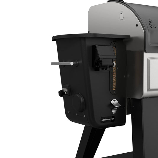Close-up of the Camp Chef Woodwind Pro 24 wood pellet grill in black and silver, showcasing its visible Smoke Box, control panel, and a transparent window displaying wood pellets—ideal for cold smoking your favorite foods.