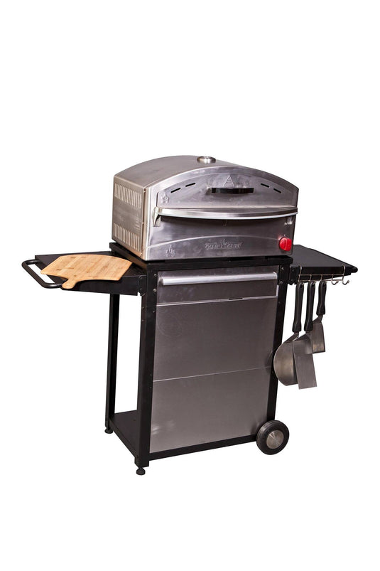 The Camp Chef Patio Cart is a stainless steel kitchen cart pizza oven with wheels, side shelves, a wooden cutting board, and hanging utensils—ideal for any outdoor kitchen or patio setup. Isolated on a white background.