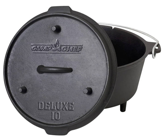 The Camp Chef Deluxe Dutch Oven is a black cast iron pot featuring a lid with embossed text, short legs, and a metal carrying handle. The lid is shown tilted against the pot.