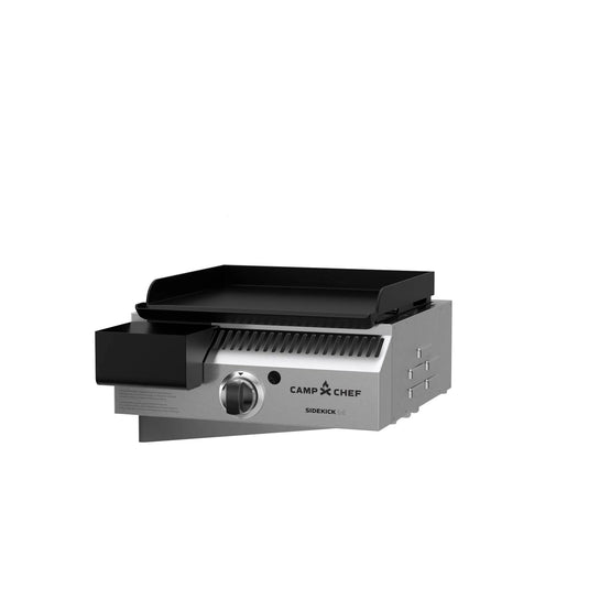 The Camp Chef Sidekicks is a stainless steel propane burner accessory with a black griddle, front control knob, and igniter button, designed for pellet grills. Shown on a white background.